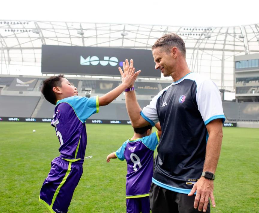 Hi five between a youth soccer athlete and coach