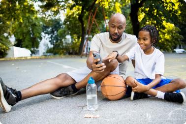 Basketball Coach showing an app on a phone to a youth to athlete