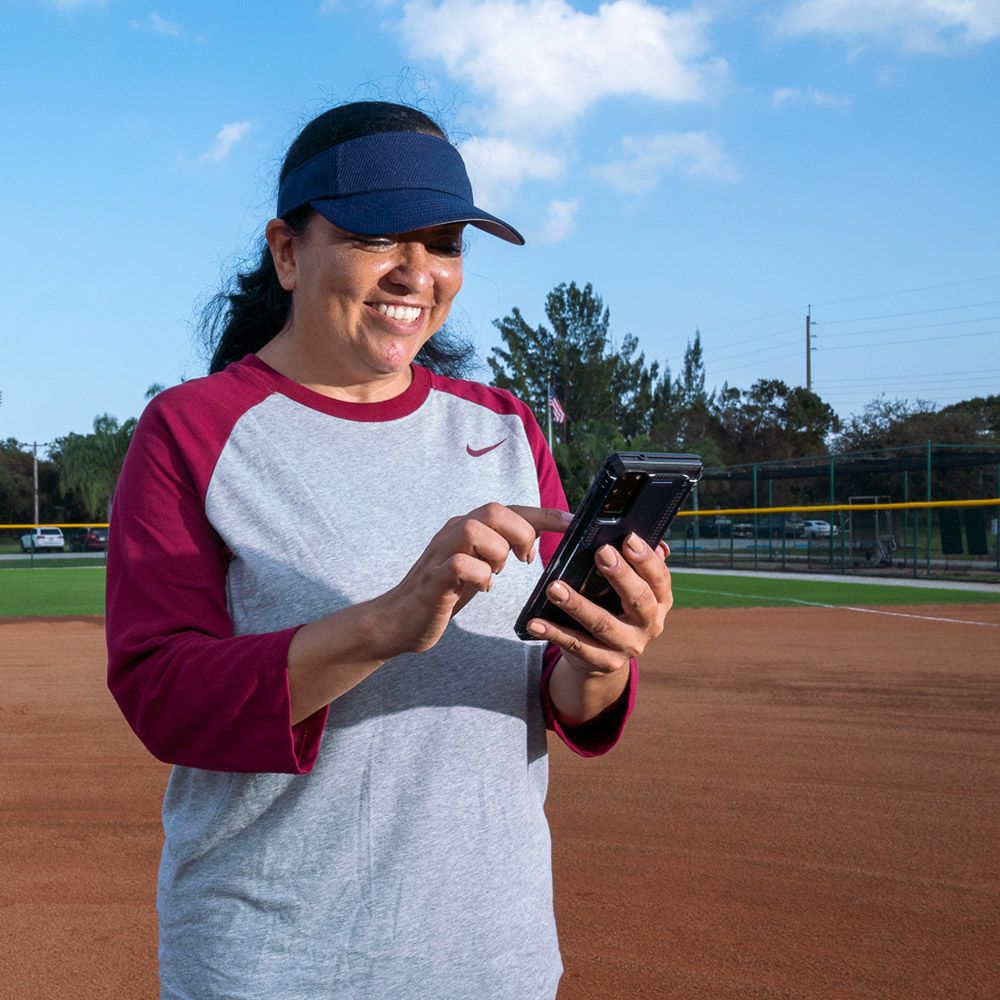 Smiling coach browsing phone on baseball field 