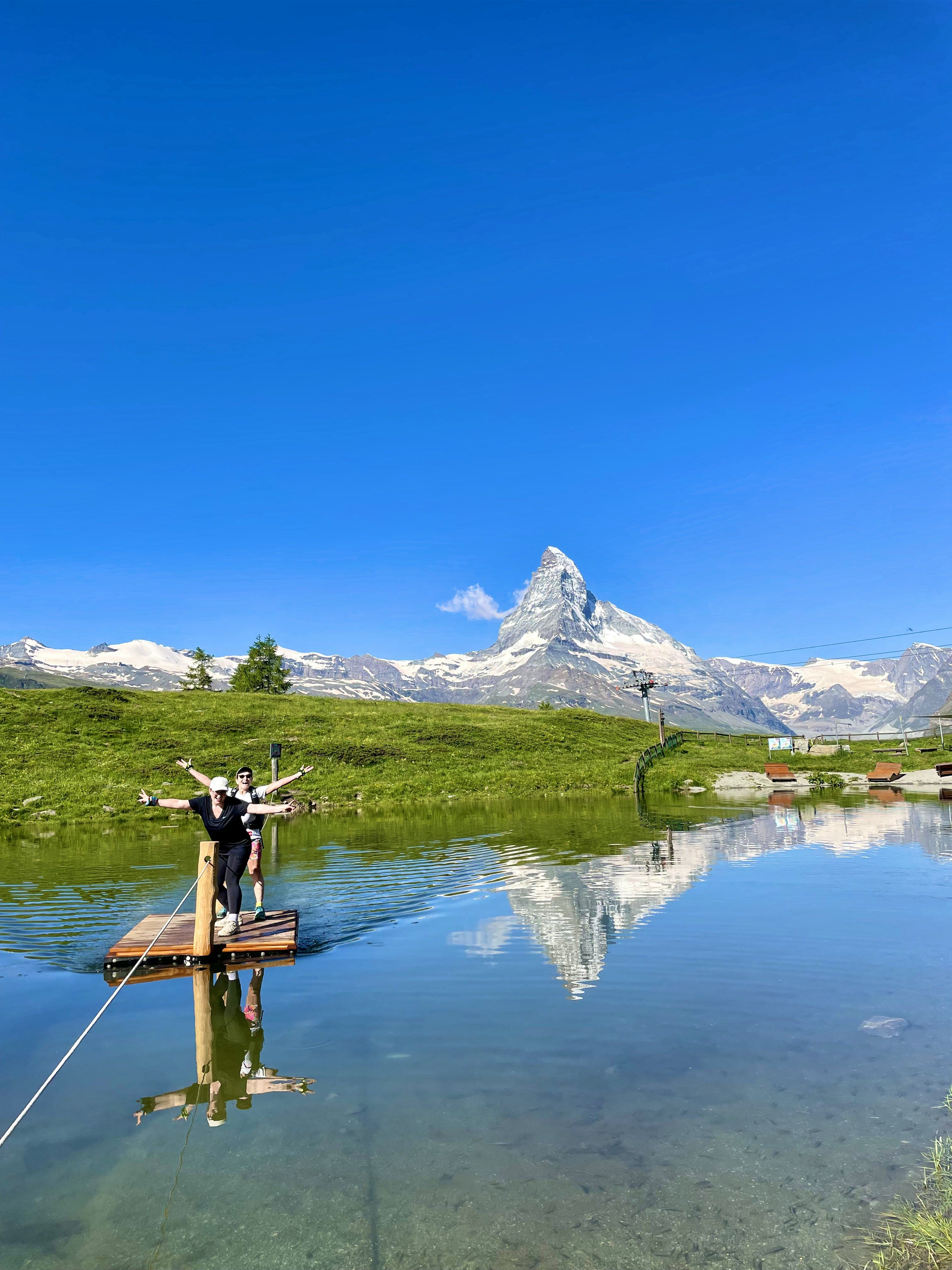 Hikers celebrating at an alpine lake with the Matterhorn reflected in crystal-clear water