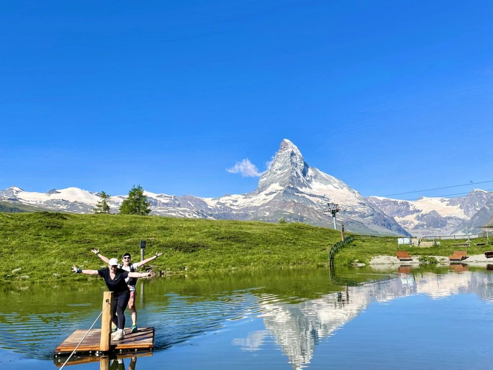 Hikers celebrating at an alpine lake with the Matterhorn reflected in crystal-clear water