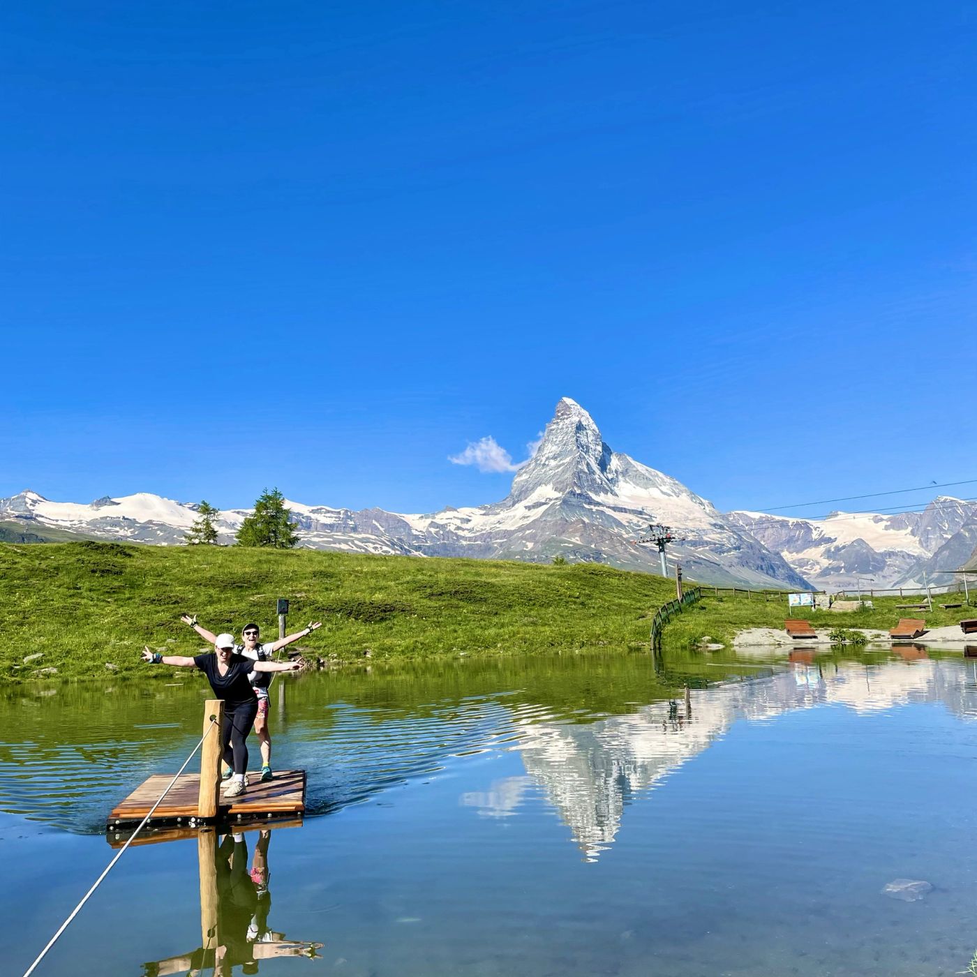Hikers celebrating at an alpine lake with the Matterhorn reflected in crystal-clear water