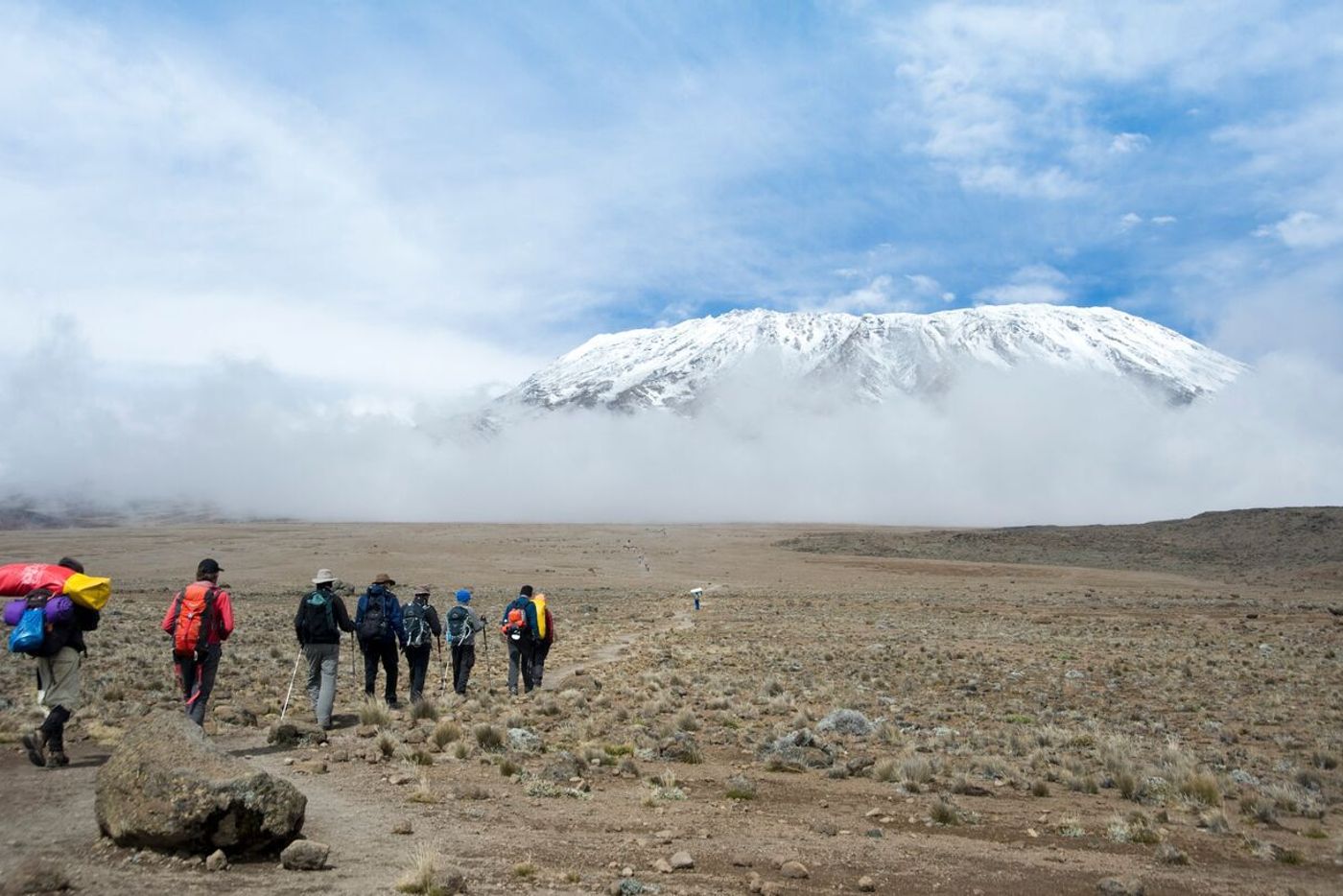 Trekkers hiking through alpine desert on Kilimanjaro with peak in background