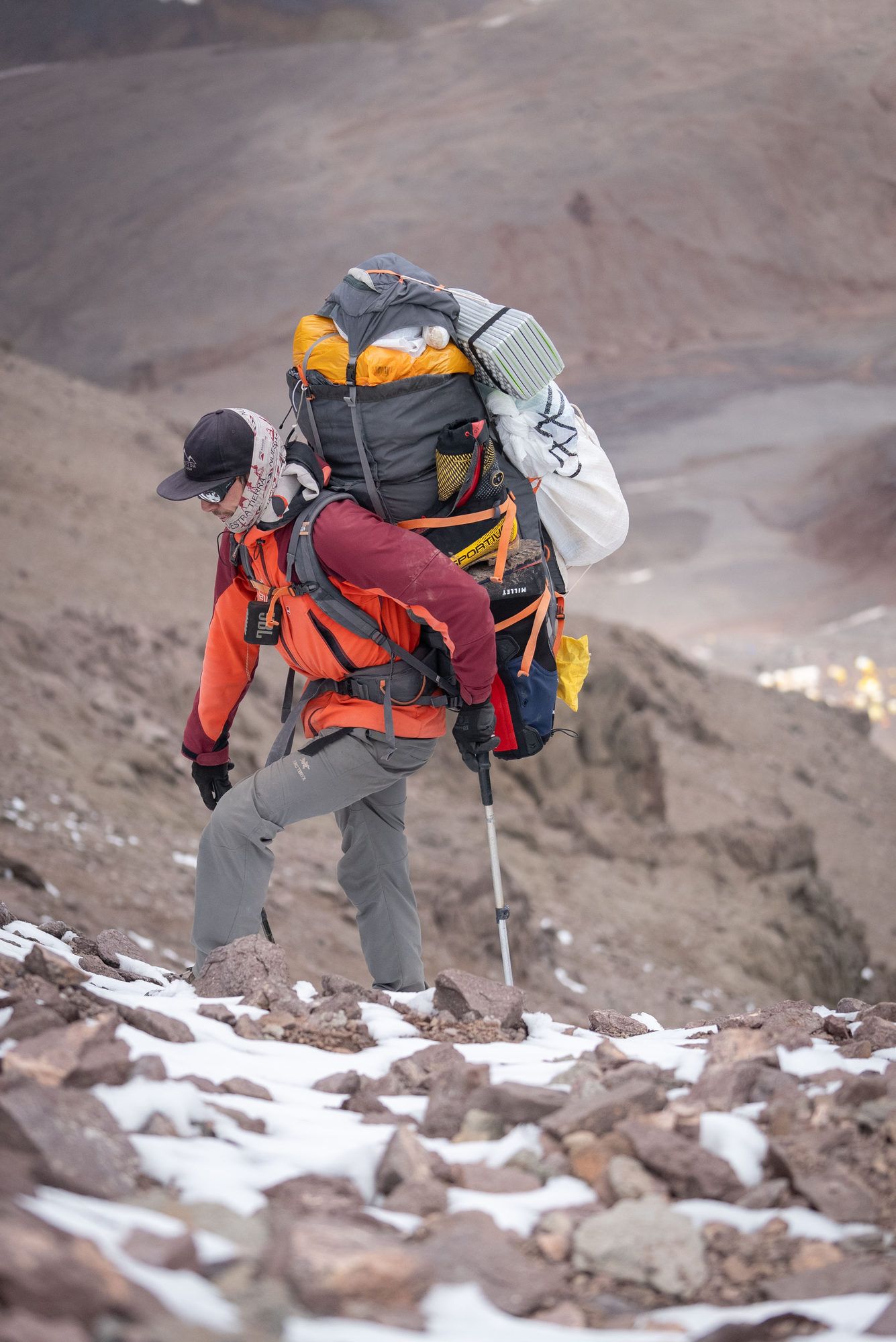 Climber with heavy pack ascending rocky terrain on Aconcagua