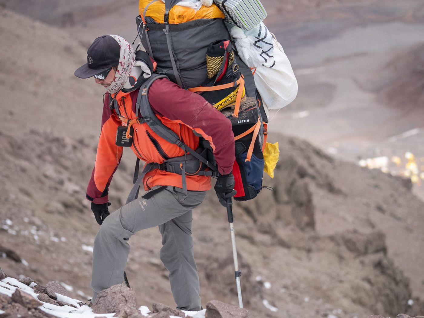 Climber with heavy pack ascending rocky terrain on Aconcagua