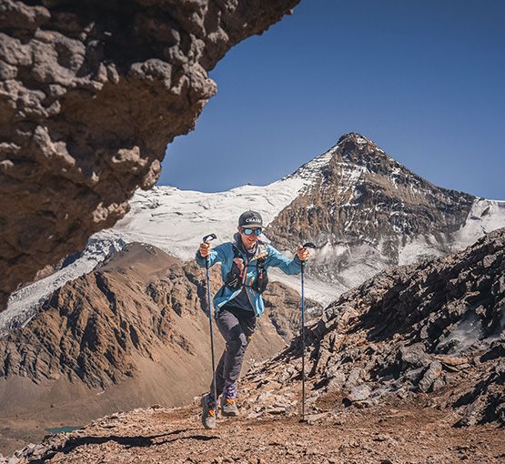 Climber approaching Aconcagua with mountain peak visible through rock arch