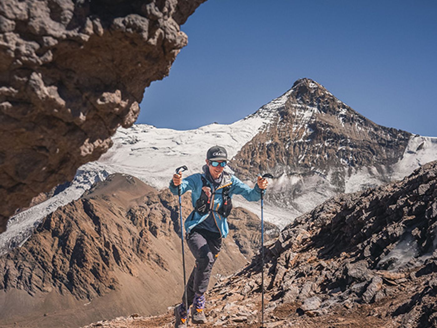 Climber approaching Aconcagua with mountain peak visible through rock arch