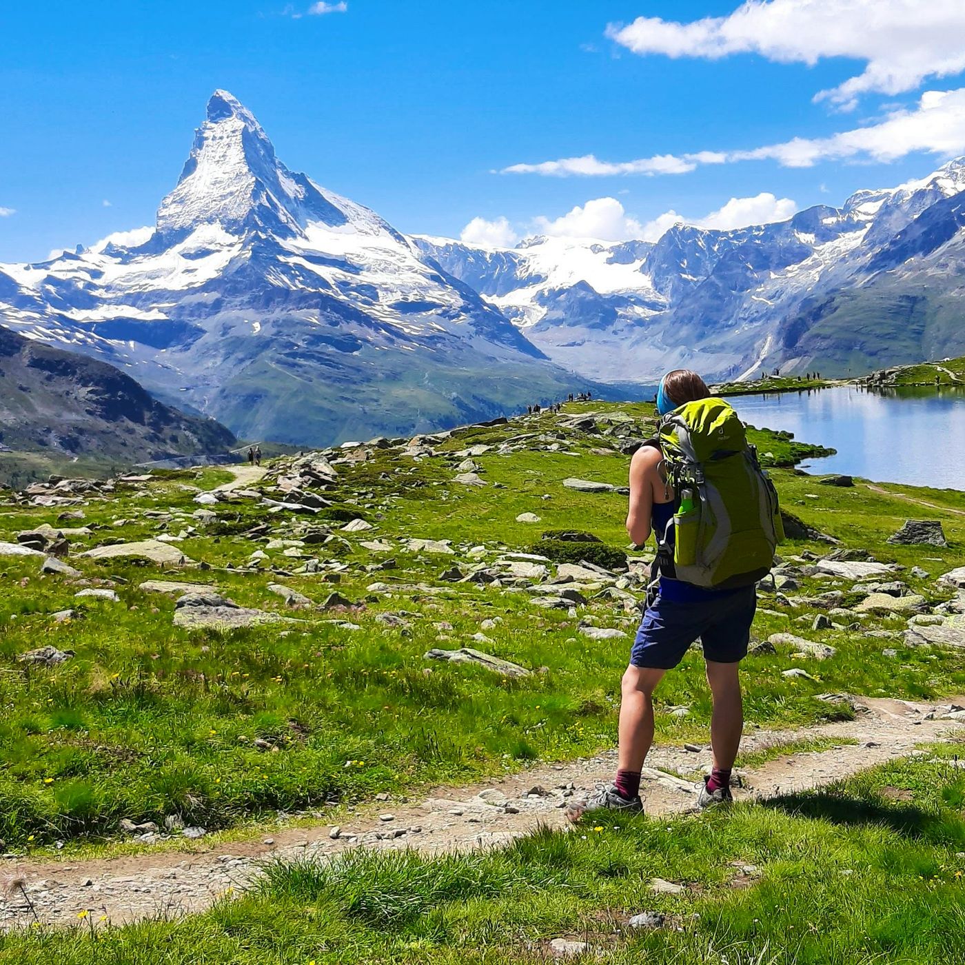 Hiker approaching Stellisee lake with the Matterhorn and Swiss Alps panorama