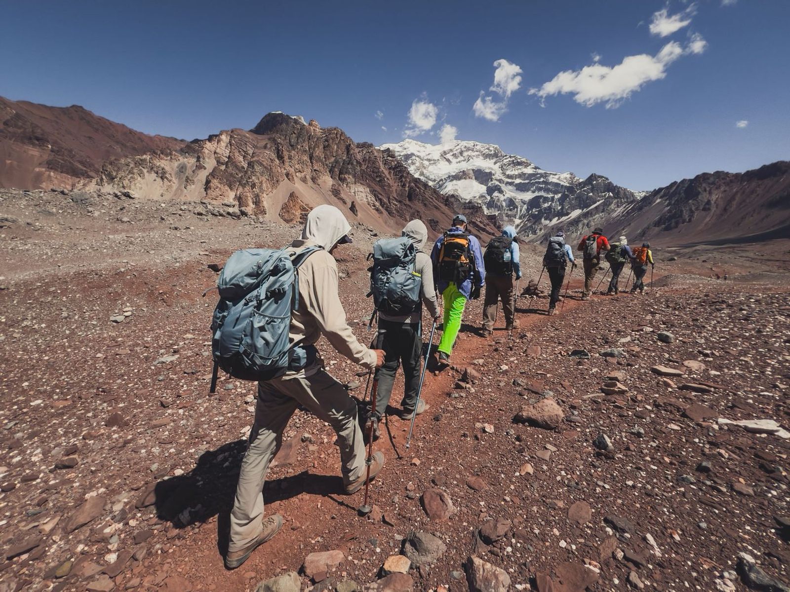 Trekkers approaching Aconcagua across rocky terrain with mountain in background