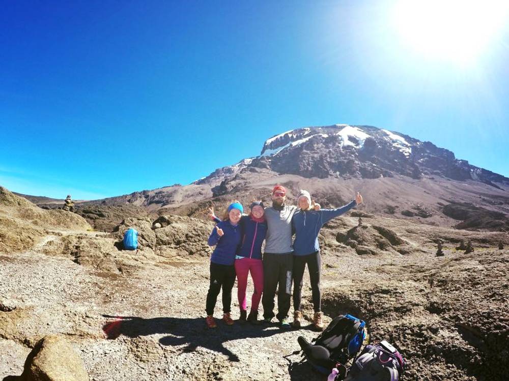 Trekkers gathering at Kilimanjaro National Park's Marangu Gate entrance, preparing to begin their ascent through the lush rainforest