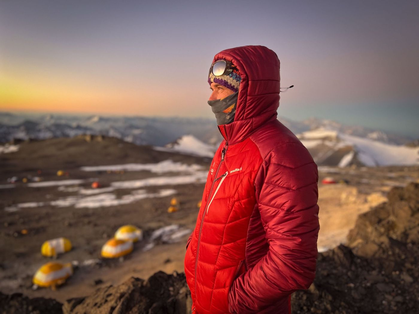 Mountaineer in red jacket surveying camp at sunset on Aconcagua