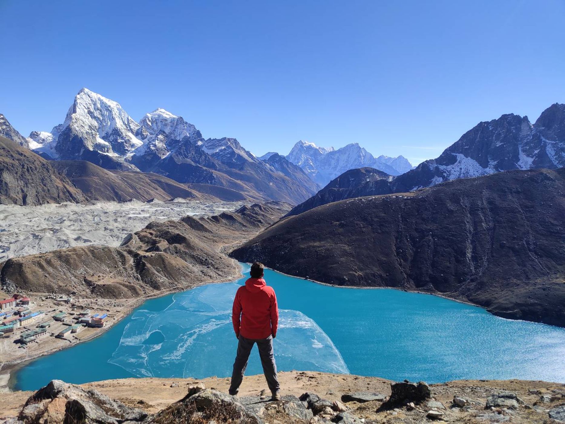 person facing a clear blue lake in nepal