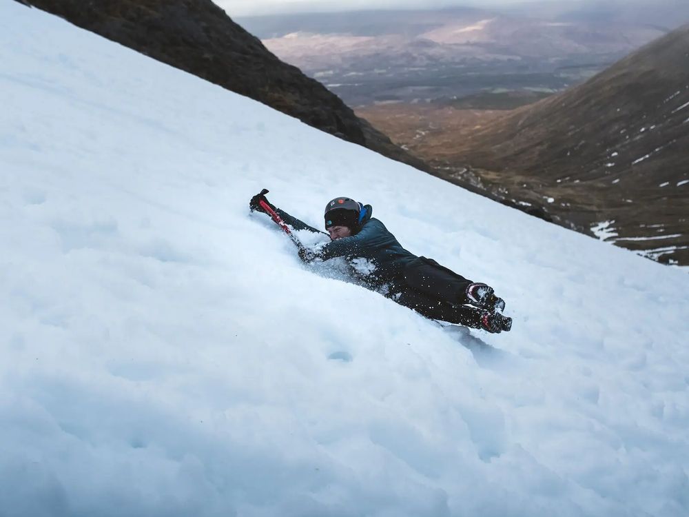 Using axe to stop sliding down mountain
