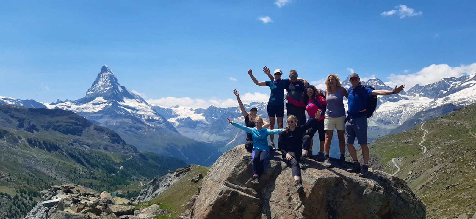 Group hiking along ridge trail with mountain panorama