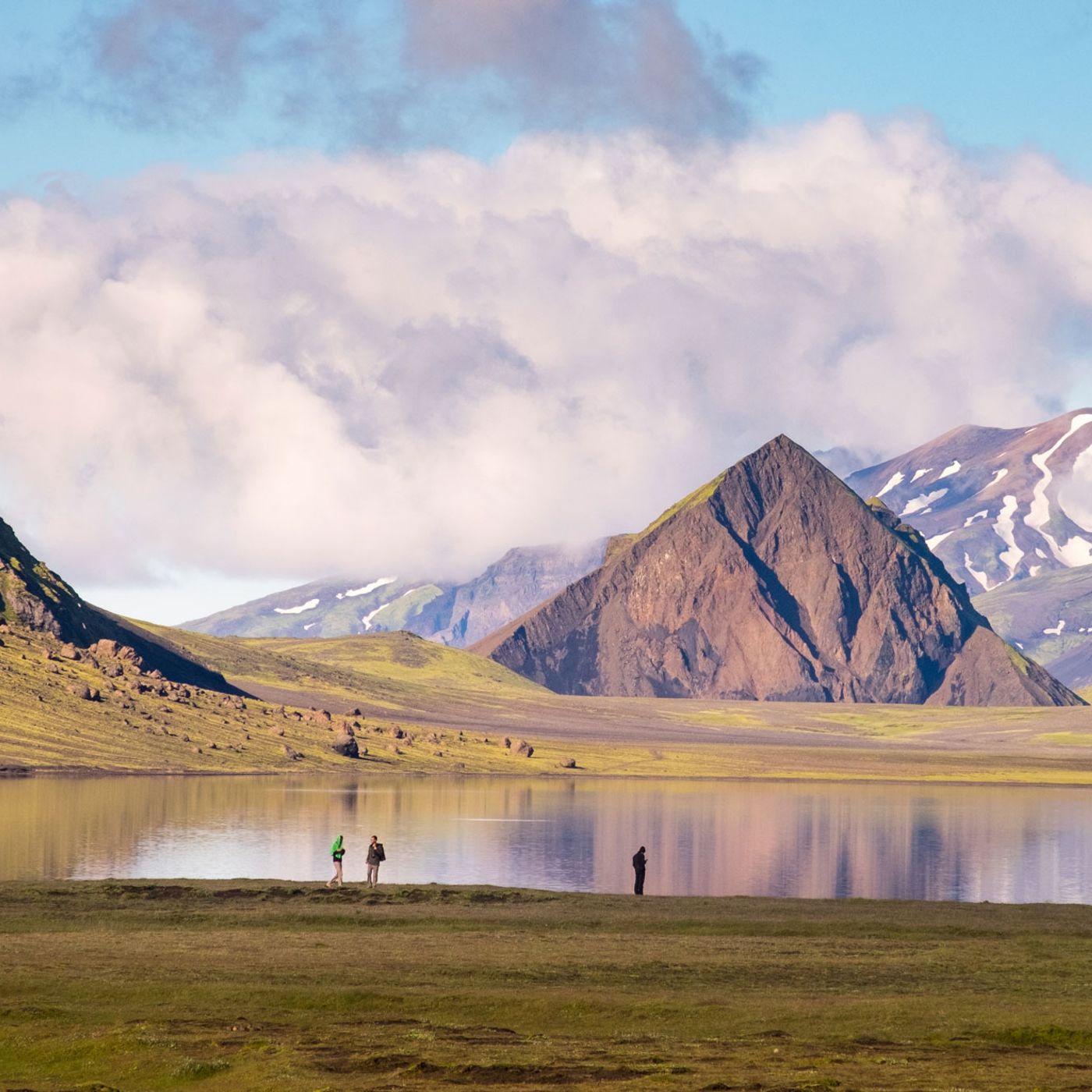 Hikers resting by pristine mountain lake in volcanic highlands