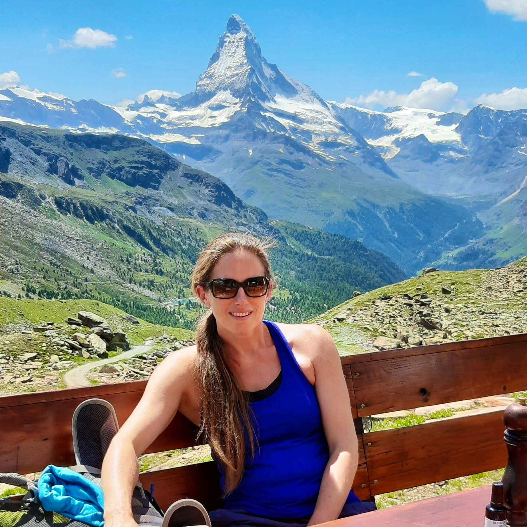 Smiling hiker relaxing on a mountain hut terrace with the Matterhorn behind