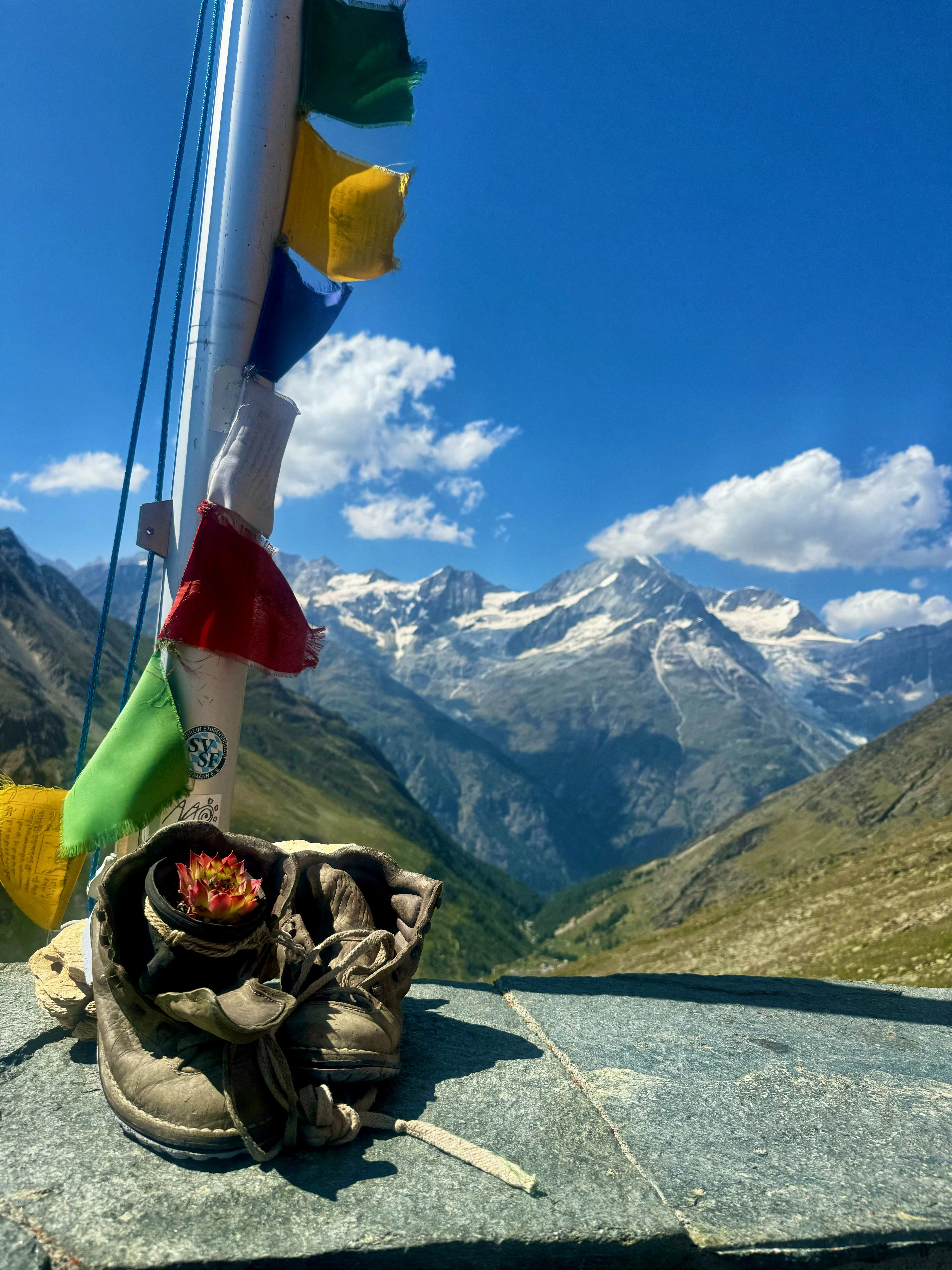 Hiking boots and prayer flags on a mountain hut terrace with panoramic valley views