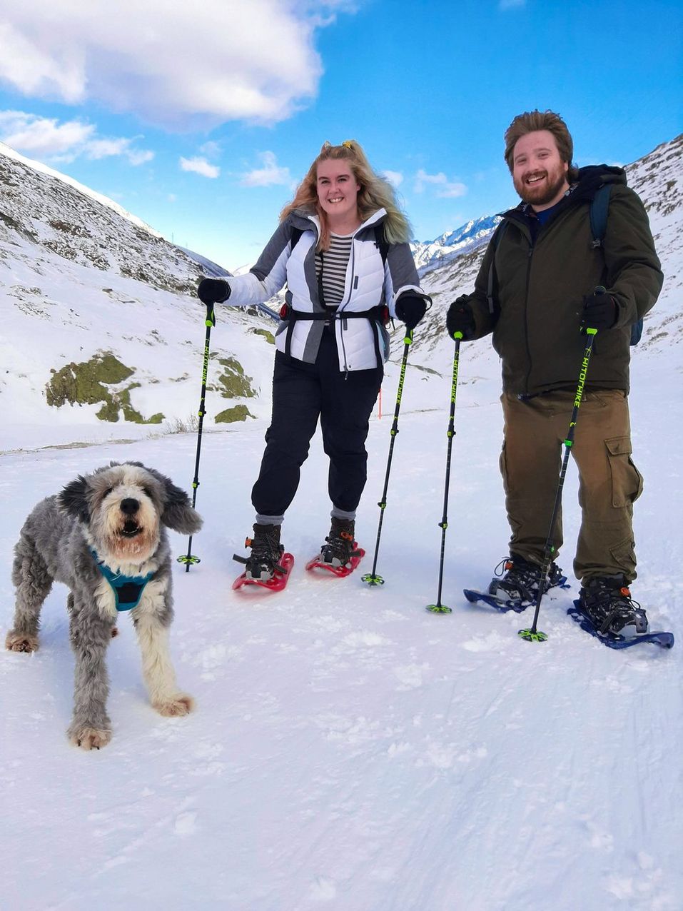 A couple snowshoeing with a dog in the Swiss Alps