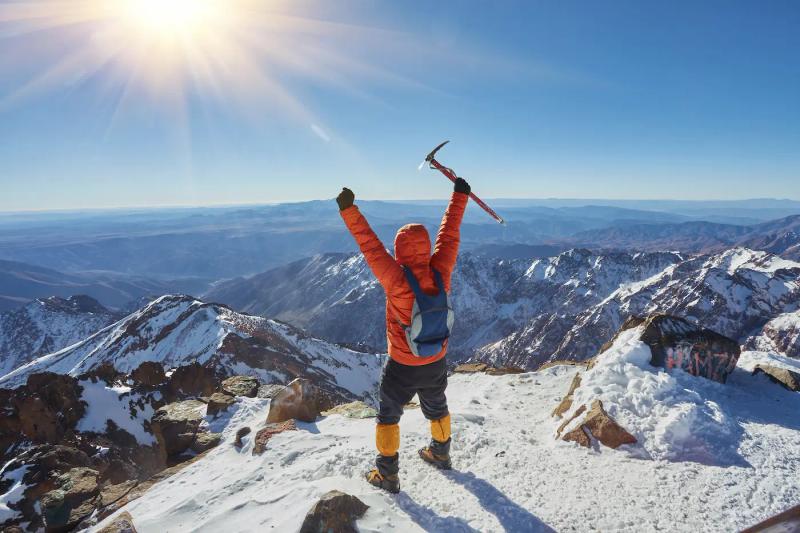 man celebrates at the summit of toubkal