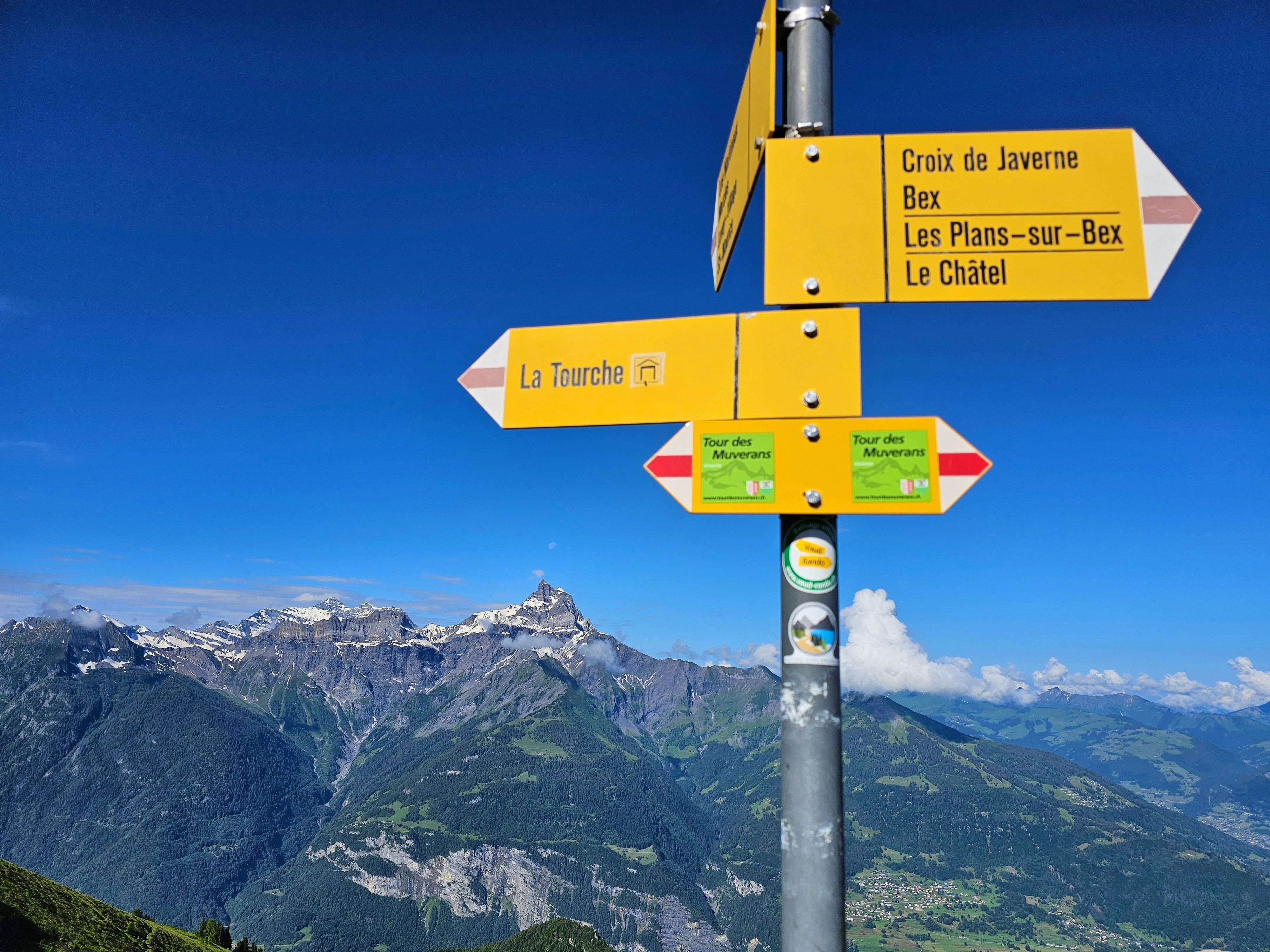 Swiss trail signpost with mountain panorama and blue sky