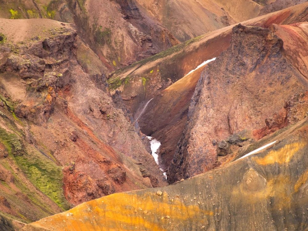 Dramatic volcanic peaks with colorful rugged terrain and glaciers in the distance