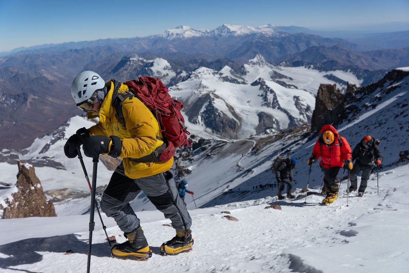 Climber in yellow jacket leading group up snowy Aconcagua slope