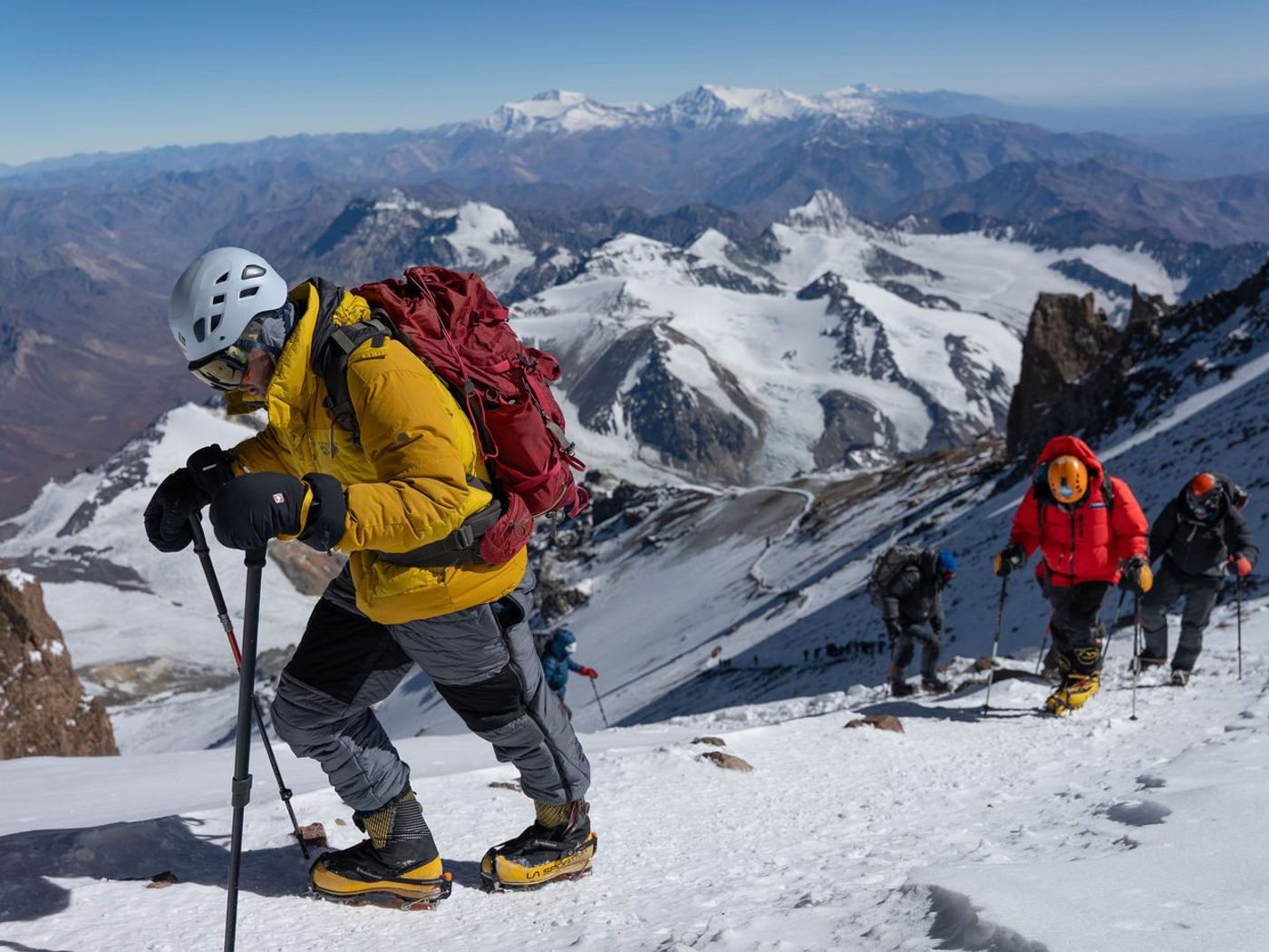 Climber in yellow jacket leading group up snowy Aconcagua slope