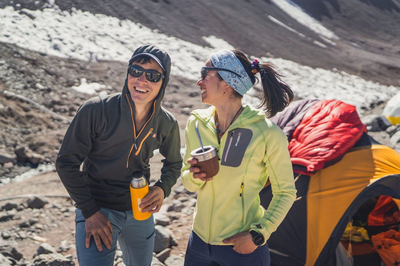 Climbers laughing over drinks at mountain camp