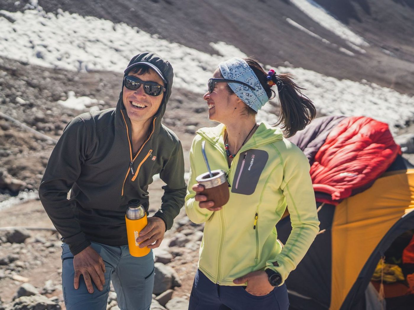 Climbers laughing over drinks at mountain camp