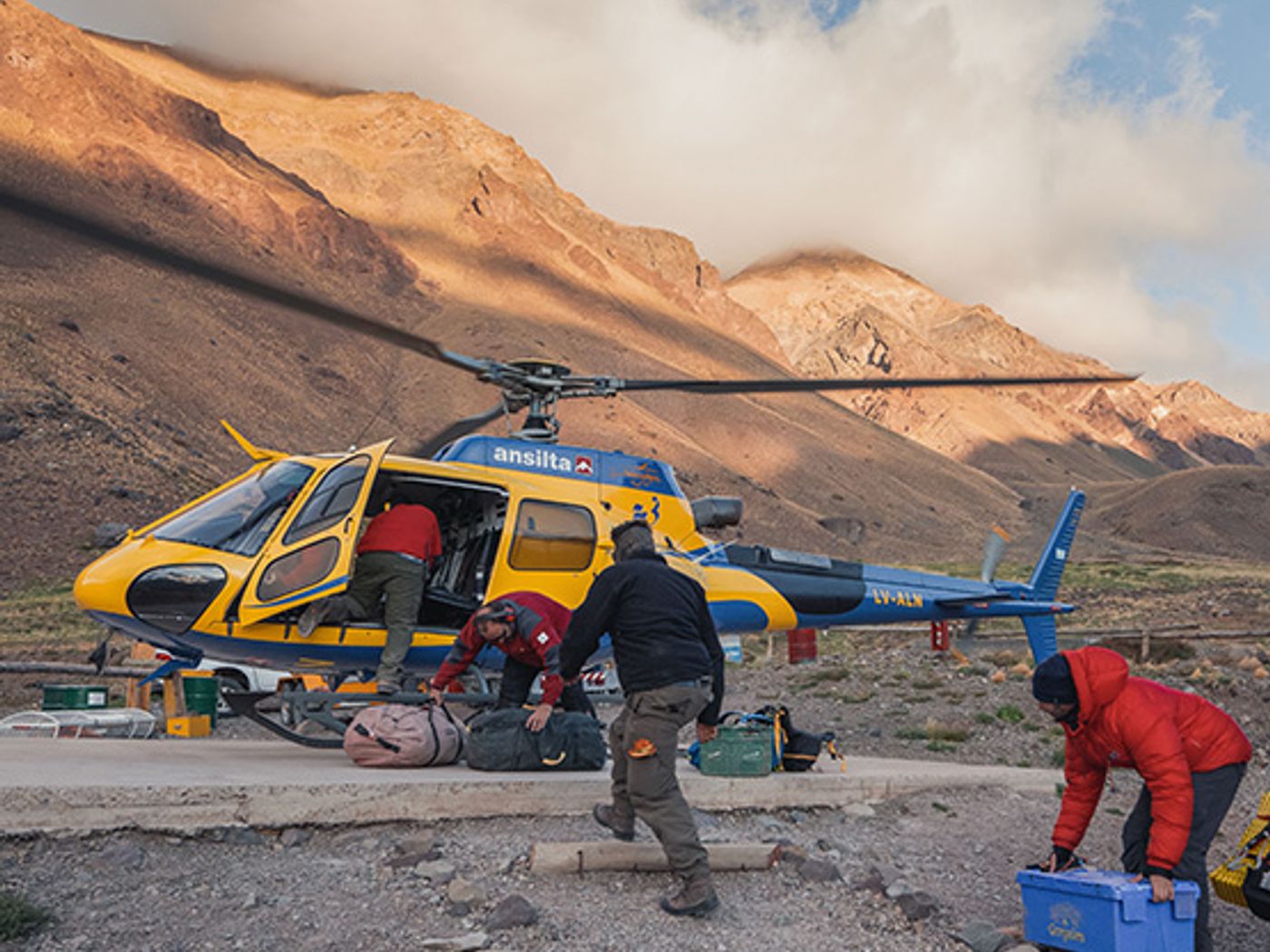 Helicopter at Aconcagua camp for expedition logistics with mountains in background