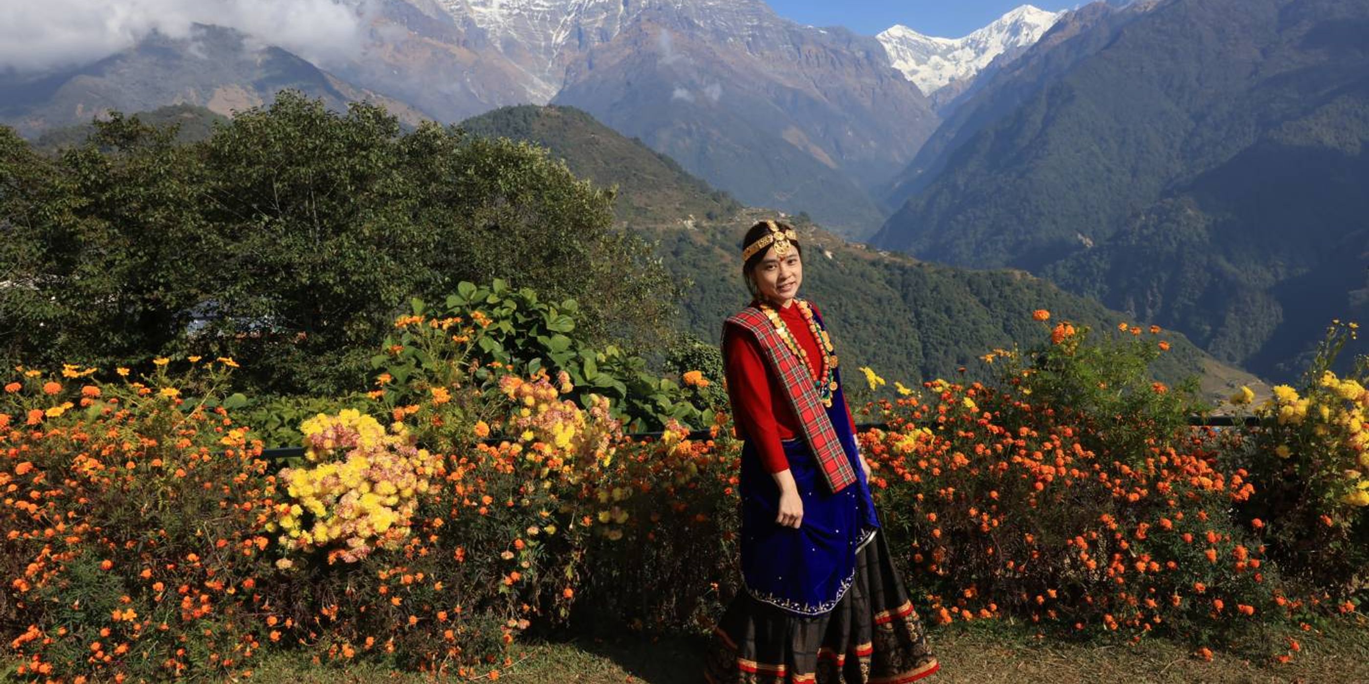 lady in traditional dress stands in front of an Annapurna viewpoint