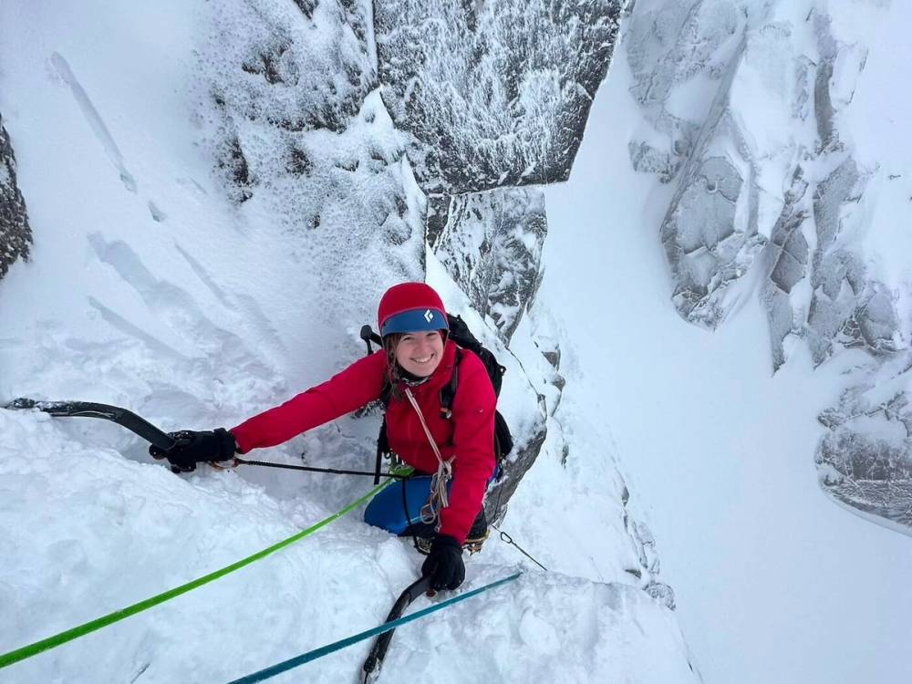 Climber ascending snowy mountain face with ice axes and crampons on Ben Nevis Scotland winter climbing course