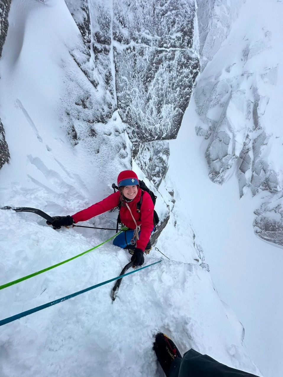 Climber ascending snowy mountain face with ice axes and crampons on Ben Nevis Scotland winter climbing course