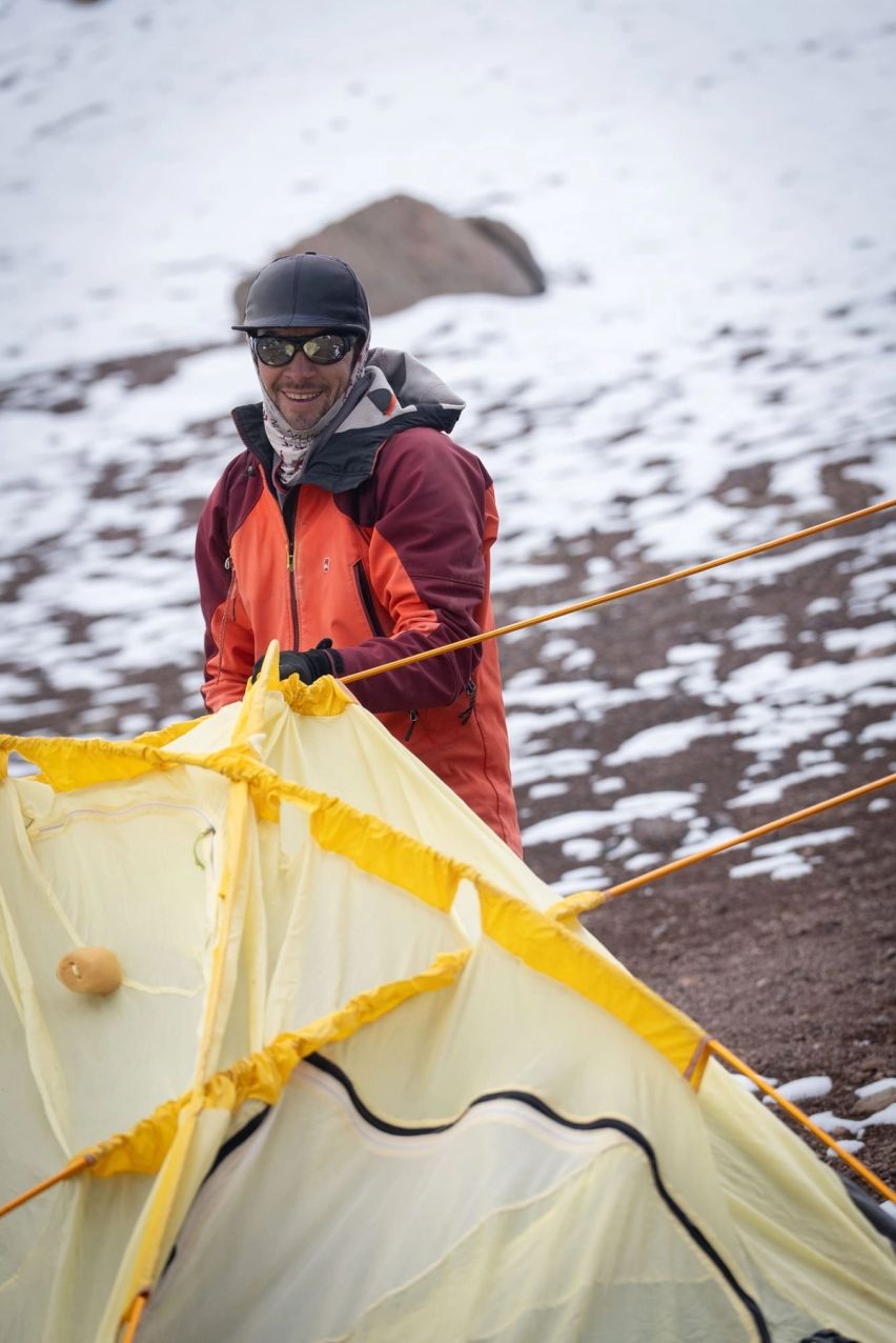 Climber setting up tent in snowy mountain camp on Aconcagua