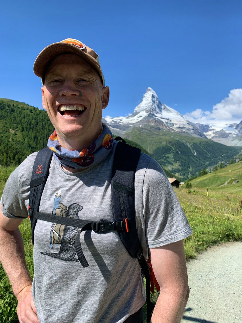 Hiker on mountain hut terrace with breakfast, Matterhorn and glaciers behind