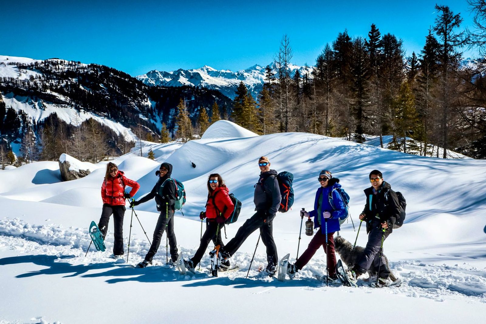 A small group snowshoeing in a line across the snowy Swiss Alps
