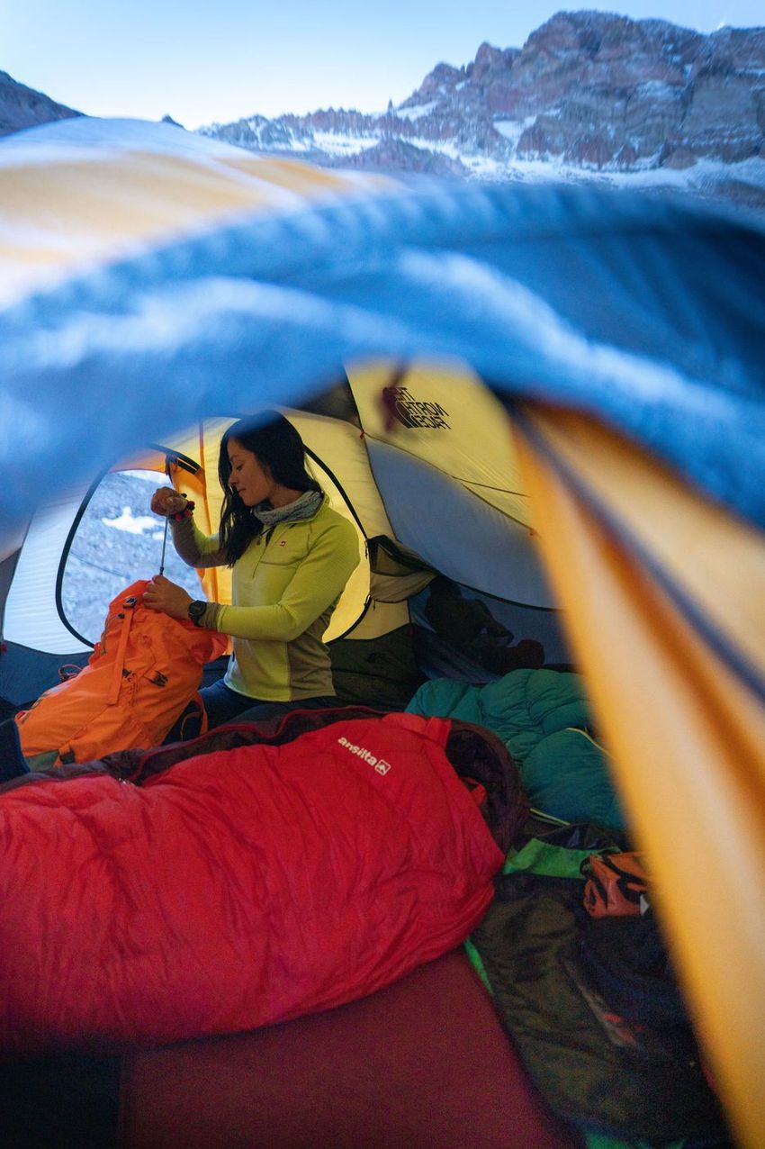 Woman packing gear outside tent on Aconcagua expedition