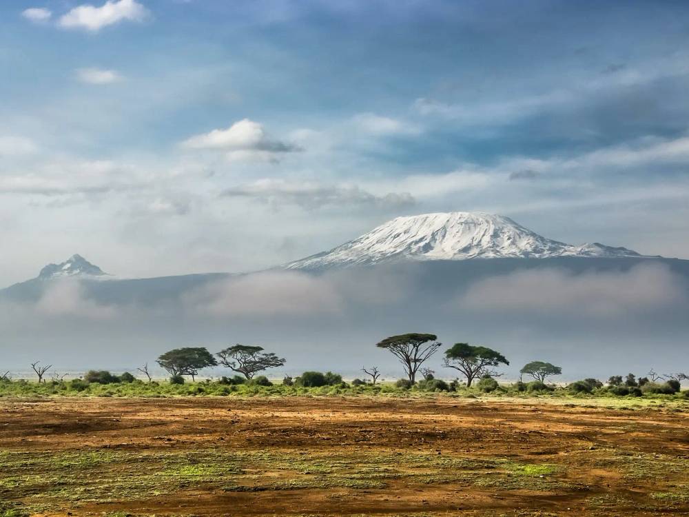 Trekkers ascending the scenic Machame Route on Mount Kilimanjaro through dramatic alpine terrain with mountain peaks in the background