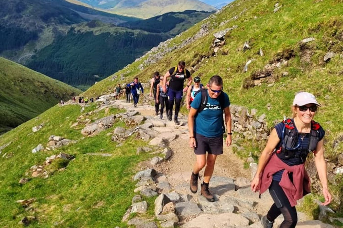 A group of happy hikers with mixed abilities celebrating on a UK mountain summit.