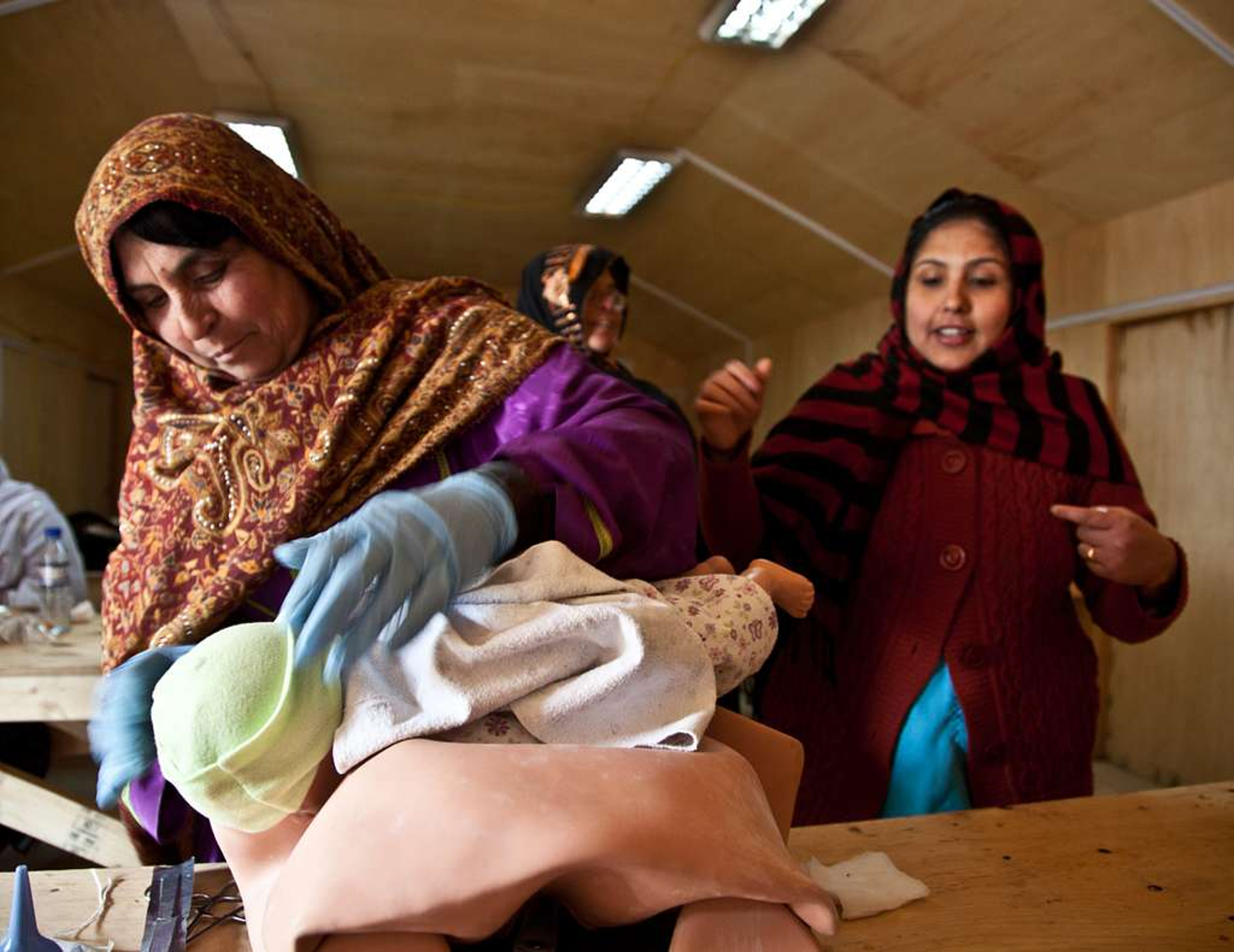 Afghan midwife providing care to a newborn during a community health session.