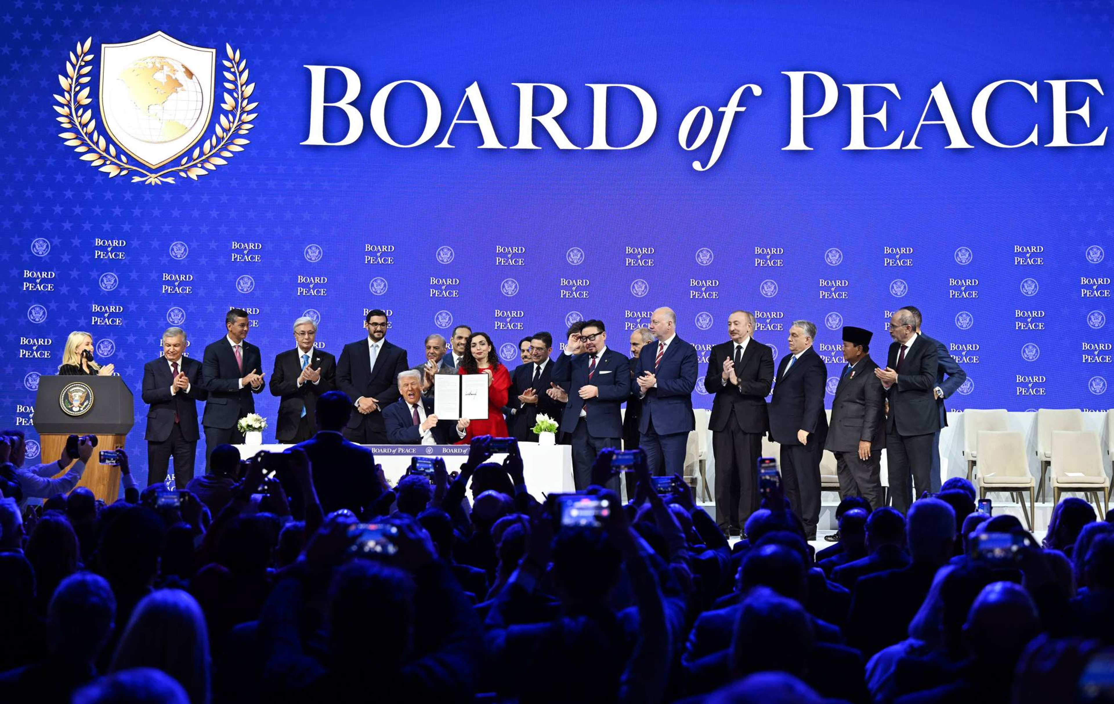 Líderes en el evento de la Junta de la Paz sosteniendo un documento firmado por la paz internacional.