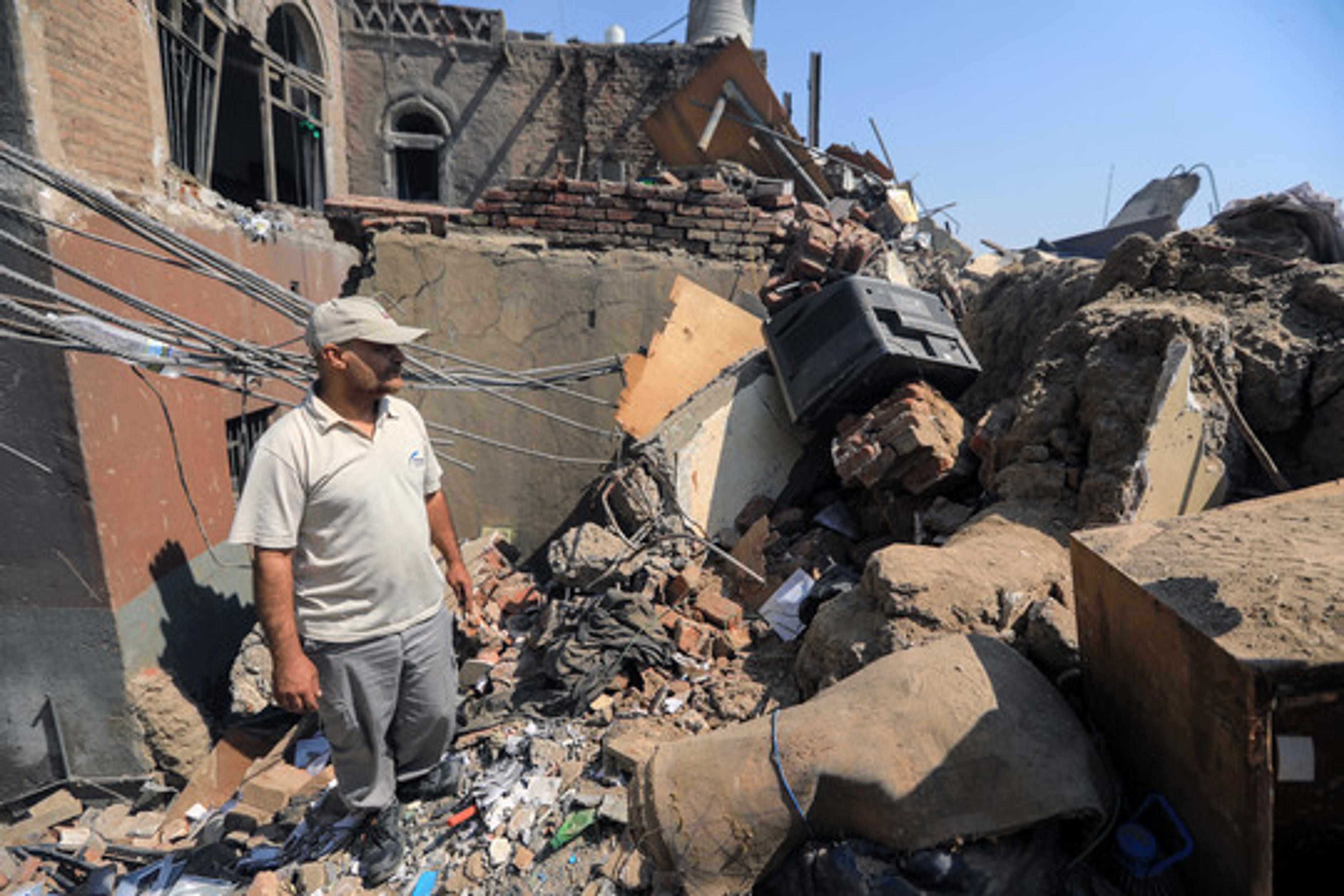 Man standing amid rubble after airstrikes in Sana’a, Yemen, 2025.