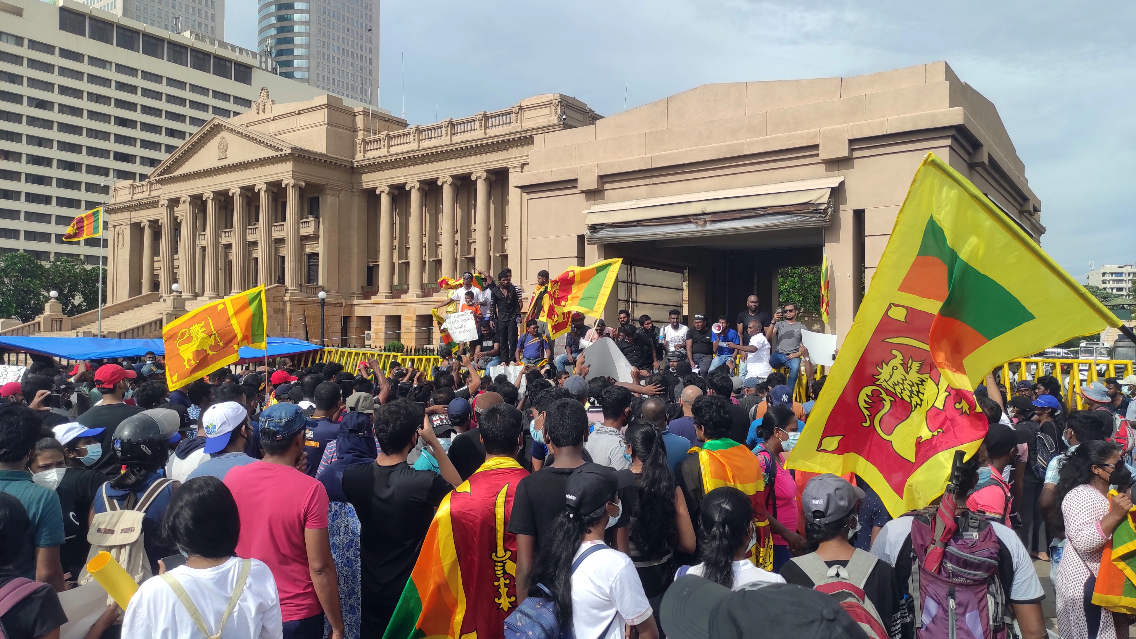 Sri Lankan youth protest with flags outside a government building.