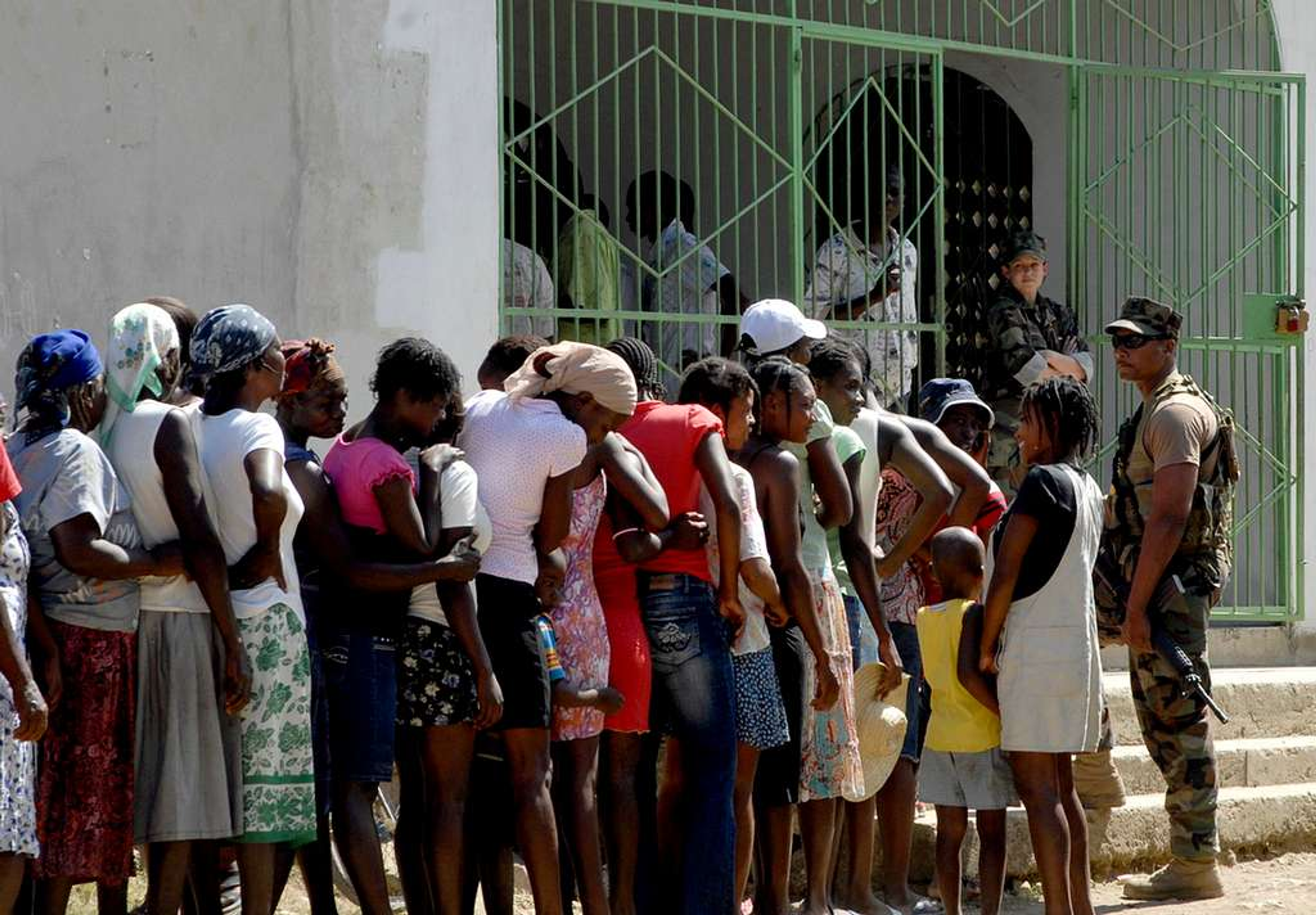 Haitian citizens waiting in line near soldiers outside a polling location in Port-au-Prince.