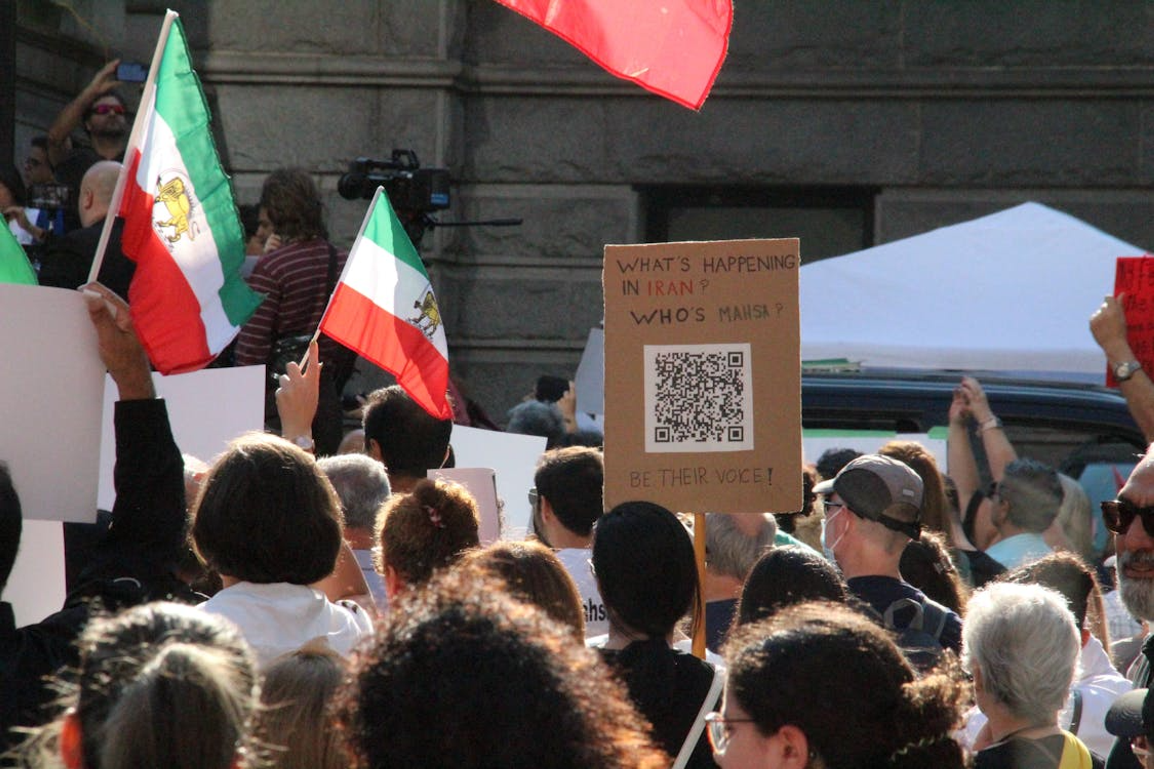Des manifestants tenant des drapeaux iraniens et une pancarte sur les manifestations en Iran et les droits de l'homme.