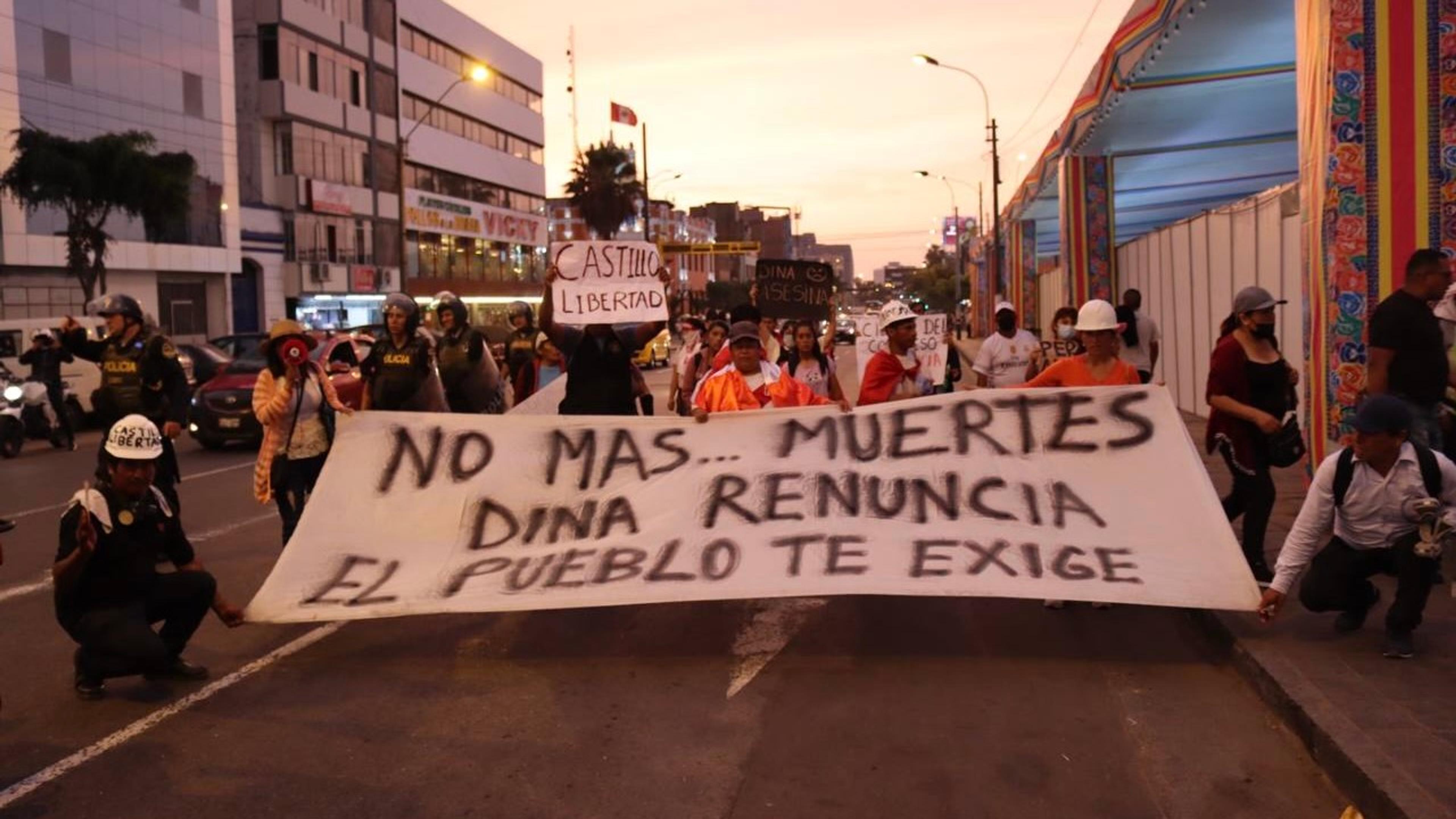 Des manifestants à Lima tiennent une banderole exigeant la démission de la présidente Dina Boluarte lors d'une marche au coucher du soleil.