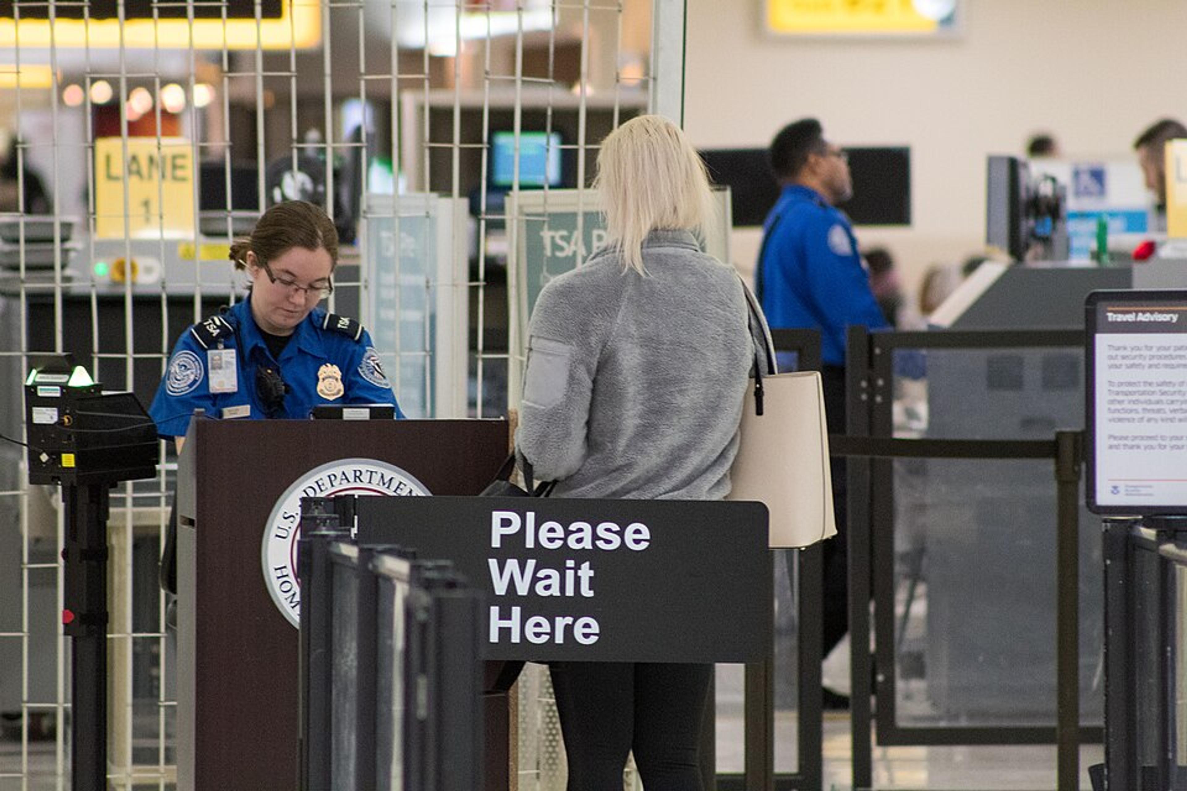 TSA officer checking a passenger’s ID at an airport security checkpoint.