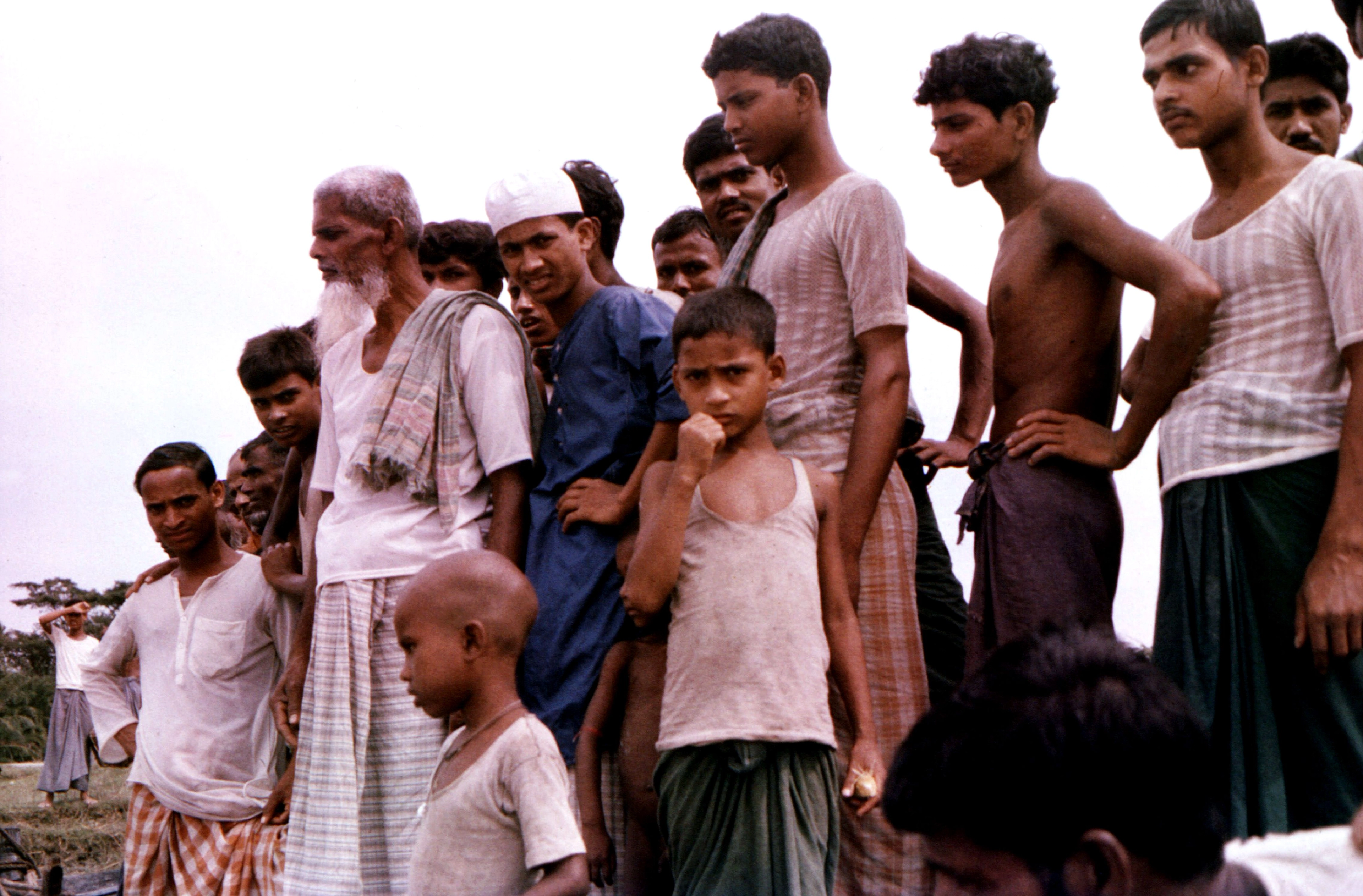 Des hommes et des enfants bangladais observant un moment communautaire local lors des élections de 2026.