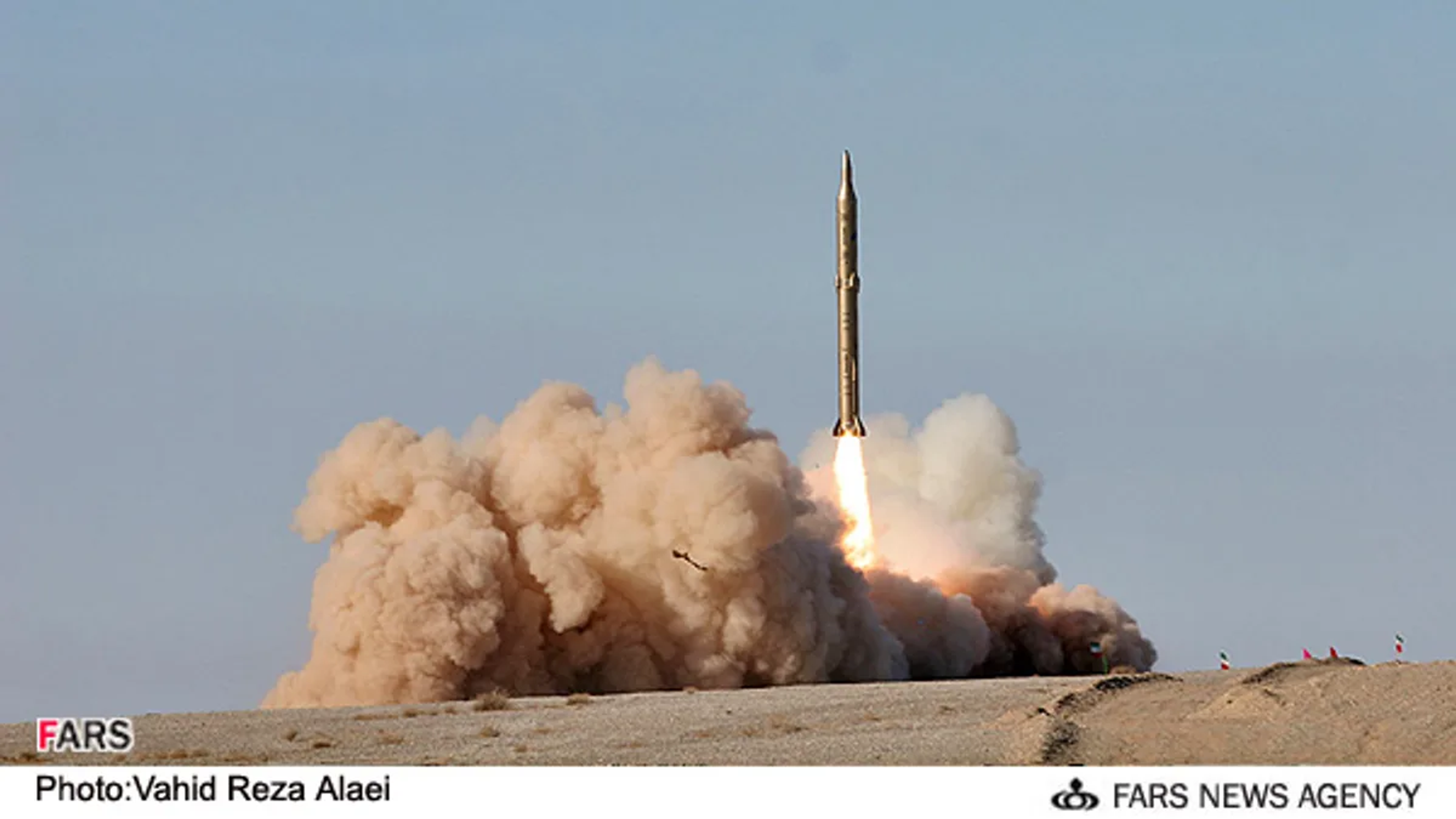 Rocket launching amid a cloud of smoke in a desert.