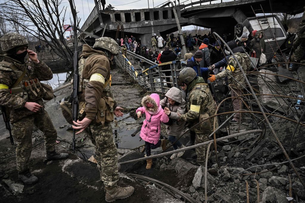 People cross a destroyed bridge as they evacuate the city of Irpin, northwest of Kyiv, during heavy shelling and bombing, 10 days after Russia launched a full-scale invasion of Ukraine, on March 5, 2022.